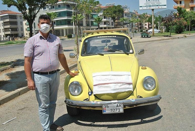 Kovid-19 tedbirlerine dikkati çekmek için arabasına maske taktı